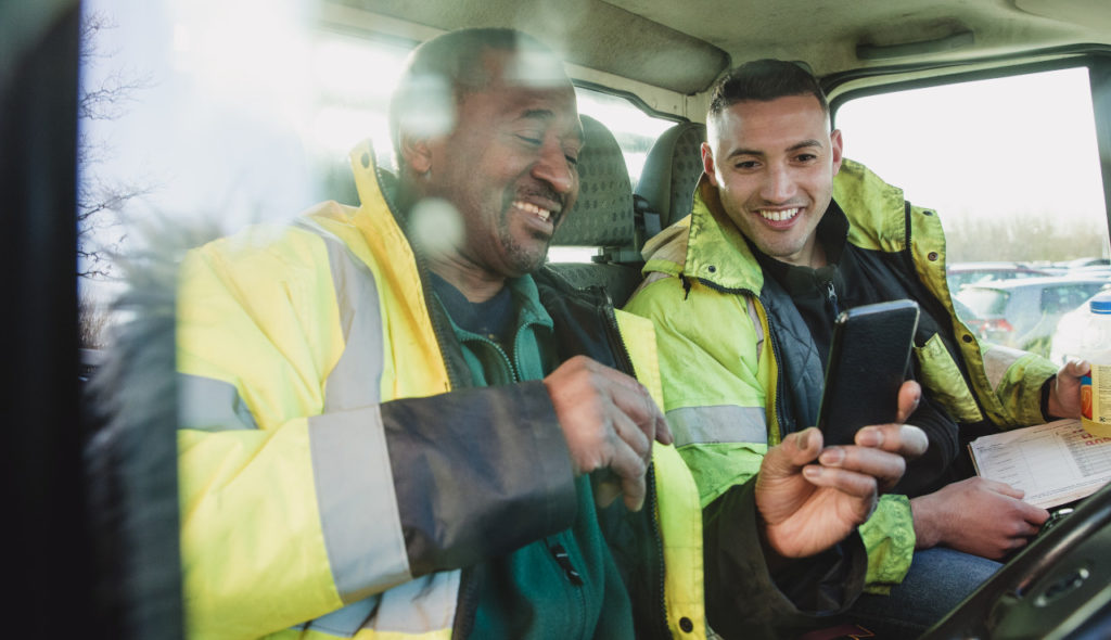Workers looking at a mobile phone. Photo: SolStock / Getty Images