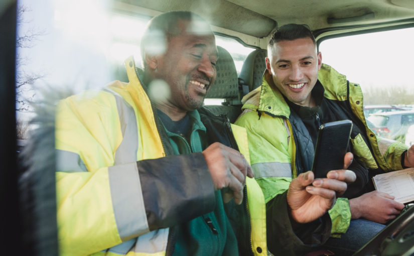 Workers looking at a mobile phone. Photo: SolStock / Getty Images